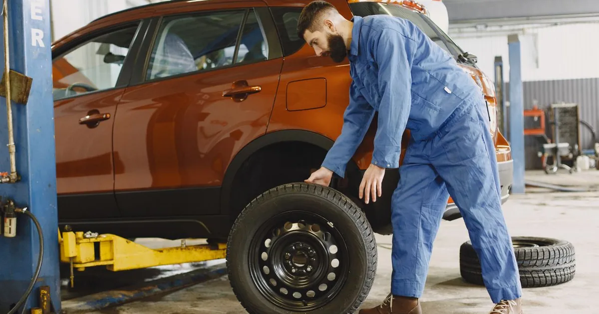 Professionnel de l'automobile changeant une roue sur un véhicule en atelier