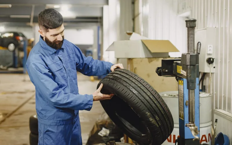 Professionnel inspectant la bande de roulement d'un pneu de voiture dans un atelier