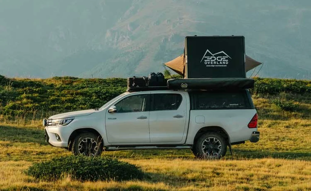 Tente de toit rigide EDGE Overland déployée sur un pick-up blanc stationné dans un paysage de montagne
